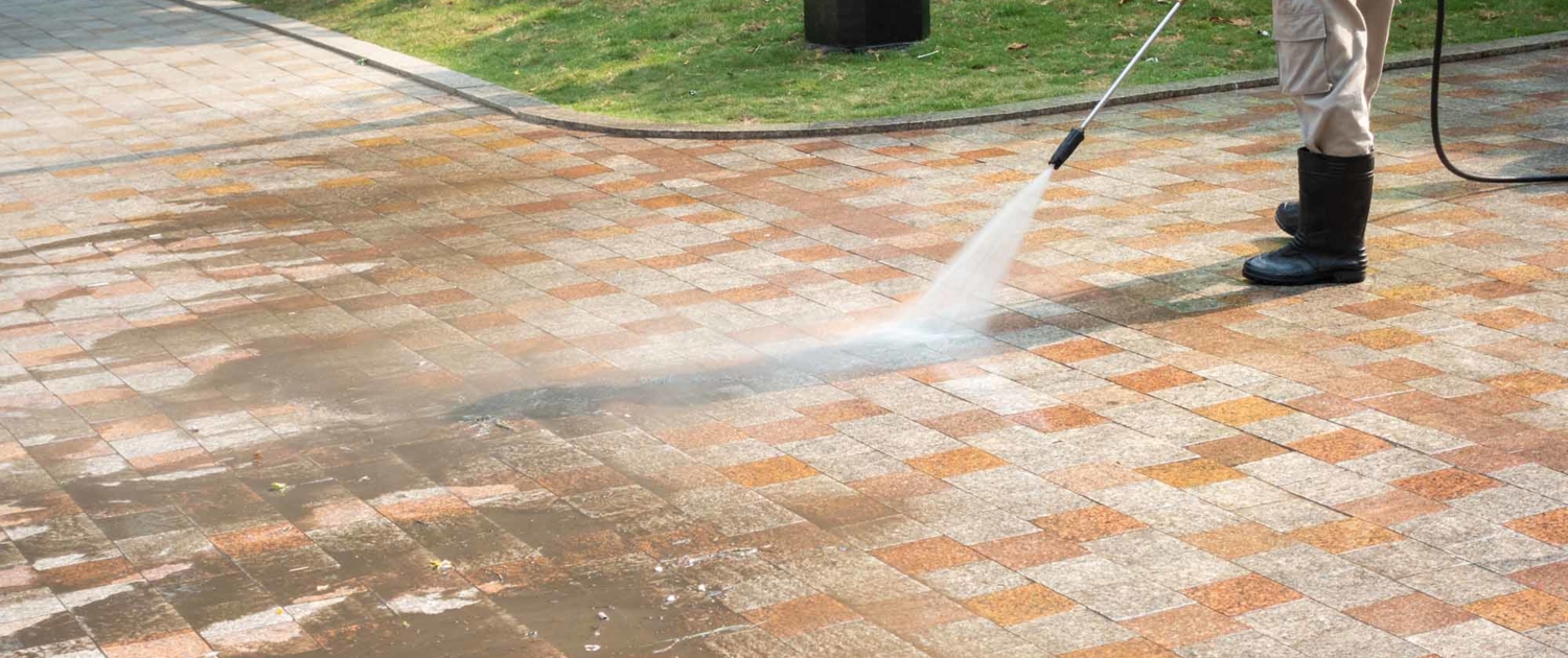 Worker power washing brick walk in a park