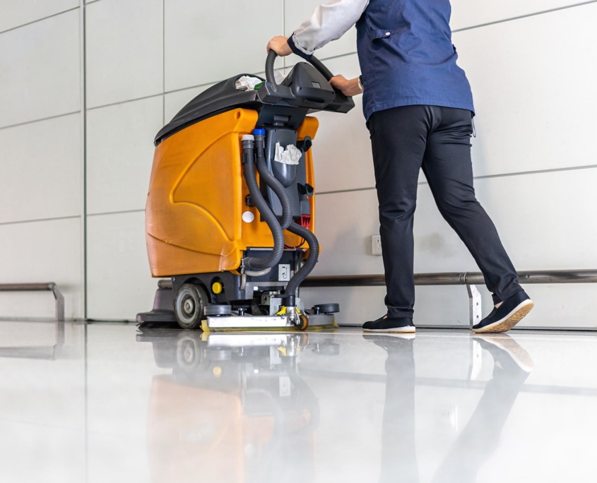 View of a cleaning worker using a floor waxing machine