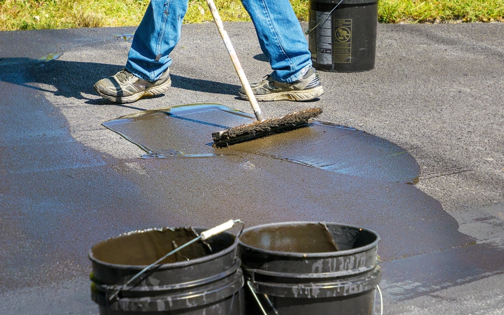View of a worker applying asphalt sealing to road