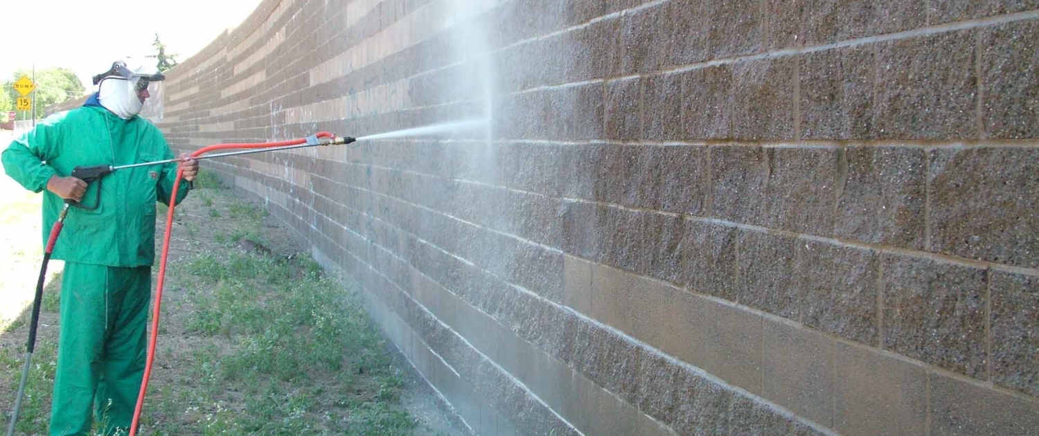 Worker cleaning off large brick wall